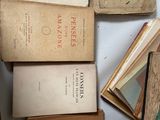 many old books on a table with a clock in the background