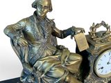 a statue of a man sitting in a chair with a clock