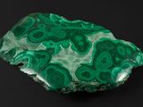 un gros plan sur un morceau de roche verte posé sur une surface noire