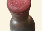 a vase with a red lid sitting on a white surface