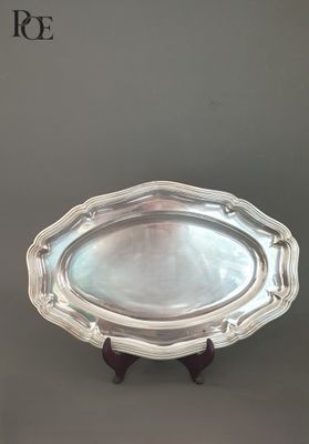 une assiette en argent posée sur un socle en bois, sur fond gris