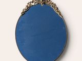 an oval mirror with a gold frame and a blue background