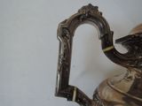 a silver tea pot with a handle on a table