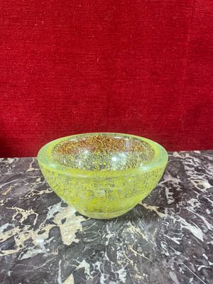 a yellow glass bowl sitting on a marble table