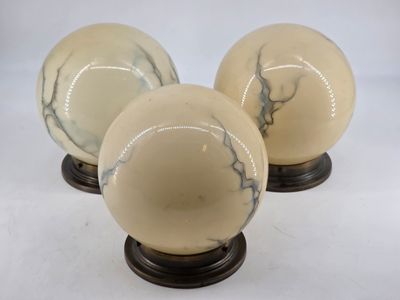 three white marble spheres on wooden bases on a white background