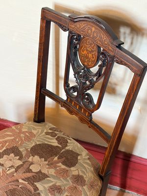 une chaise en bois sur laquelle est posé un coussin recouvert d'un tissu à motifs floraux