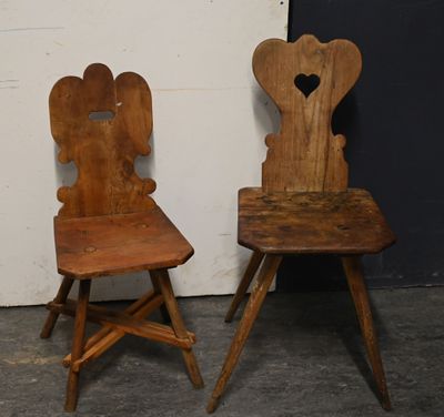 pair of wooden chairs with heart shaped backrests against a white wall
