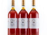 three bottles of wine are lined up on a white surface