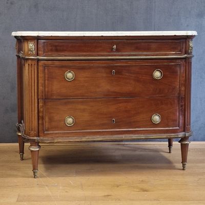 a wooden chest of drawers with marble top on a hard wood floor