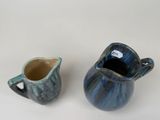 two small blue and white pitchers sitting next to each other
