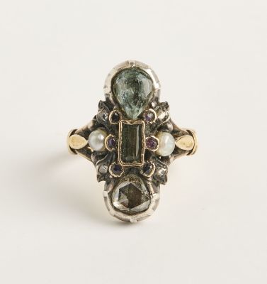 un gros plan d'une bague ornée d'une tourmaline verte entourée de perles