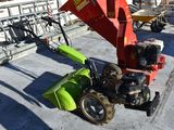 a green and red tractor and a red machine on the ground