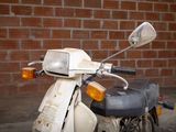 a moped that is parked in front of a brick wall