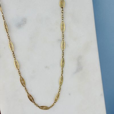 un gros plan d'un collier en or posé sur une surface en marbre