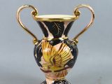 un vase noir et doré posé sur une table