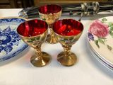 three wine glasses sitting on a table next to a plate