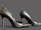 a pair of black high heeled shoes on a grey background