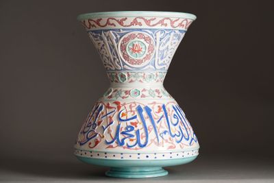 a vase with arabic writing on it sitting on a table