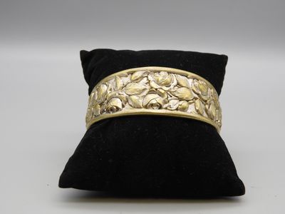 un gros plan d'un bracelet en or posé sur un coussin noir