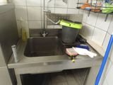 a sink in a kitchen with a trash can and a brush