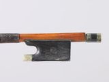 un archet de violon avec un manche en bois posé sur une surface blanche