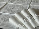 four folded napkins on a table with a monogram on them