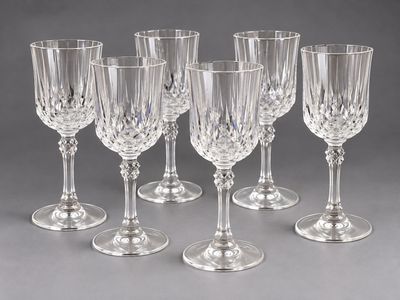 six verres à vin en cristal alignés sur une surface grise