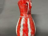 a red and white vase sitting on a gray surface