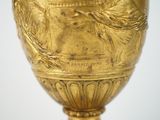 a gold vase with a woman on it on a table