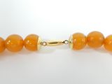 a close up of an orange beaded necklace on a white surface