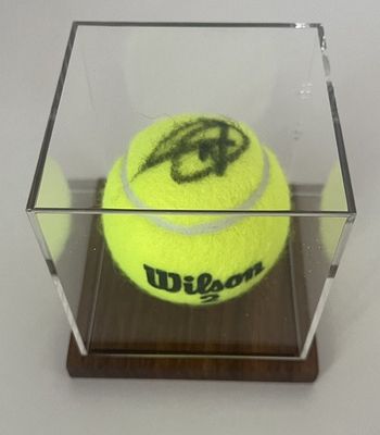 une balle de tennis jaune dans une boîte transparente posée sur une table