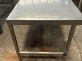 une table en acier inoxydable dans un entrepôt où se trouvent des tables et des bancs