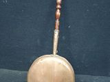 a metal pan with a wooden handle on a black surface