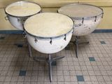 three drums sitting on a tiled floor in a room