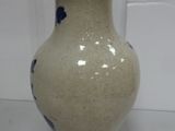 a white vase with blue flowers on it sitting on a table