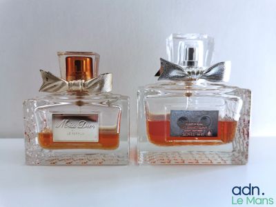 two bottles of perfume sitting next to each other on top of a table