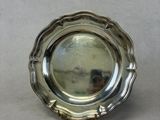 an antique silver plate on a table with a reflection of a person in the mirror