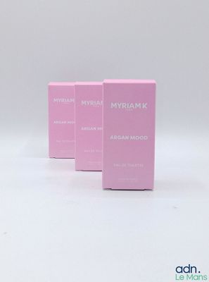 trois coffrets de parfum roses posés sur une surface blanche