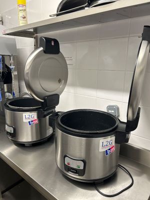 un plan de travail en acier inoxydable sur lequel sont posés des casseroles et des poêles, dans une cuisine professionnelle