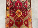 an old rug hanging on a wall with a wooden hanger