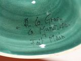a green bowl with writing on it sitting on a table