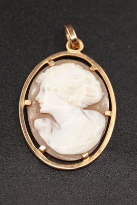 un pendentif camée doré et blanc représentant le visage d'une femme
