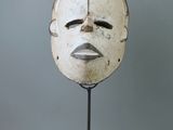 une image représentant un masque blanc posé sur un socle noir
