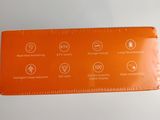 a close up of an orange plastic ruler on a white surface