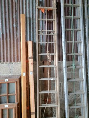 une échelle appuyée contre un mur, à côté d'un tas de vieilles fenêtres