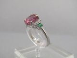 un gros plan d'une bague rose et verte posée sur un socle transparent