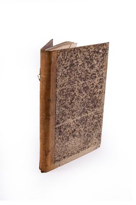 un vieux livre à la couverture marron posé sur une surface blanche