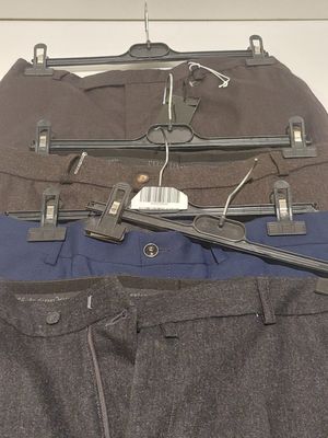 trois paires de pantalons suspendues à un cintre accroché au mur