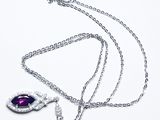 collier avec une pierre violette et une chaîne en argent sur fond blanc