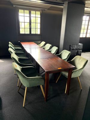 une longue table entourée de nombreuses chaises dans une pièce